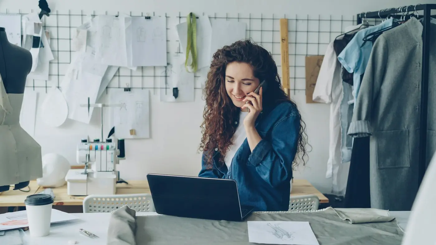 A designer on the phone with a client at her laptop