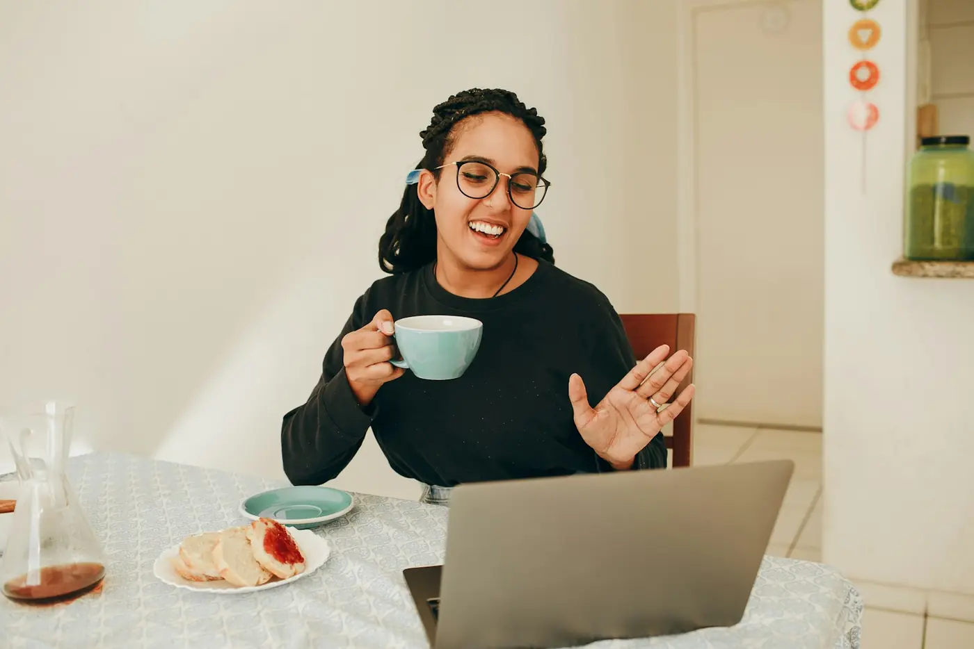 A store owner laughing over coffee at her laptop
