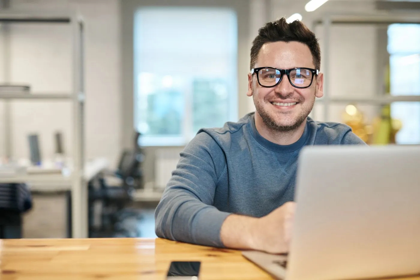A smiling man in glasses at his laptop