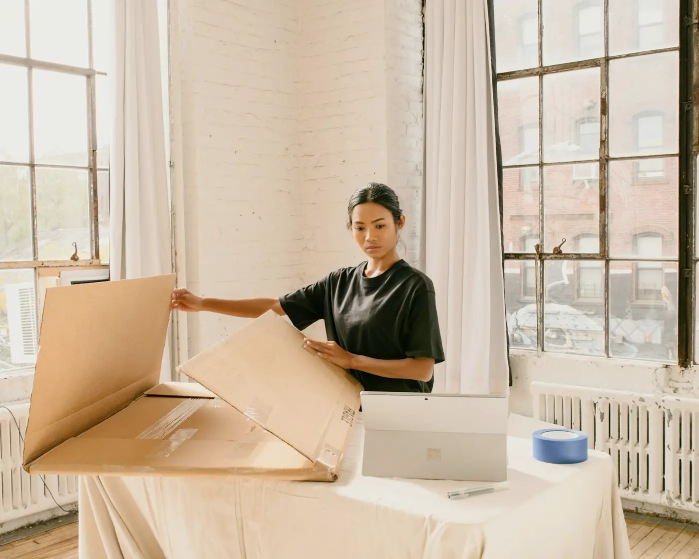 A woman packing boxes in a sunny studio