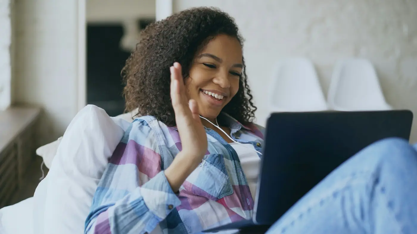 A woman waving hello on a video call