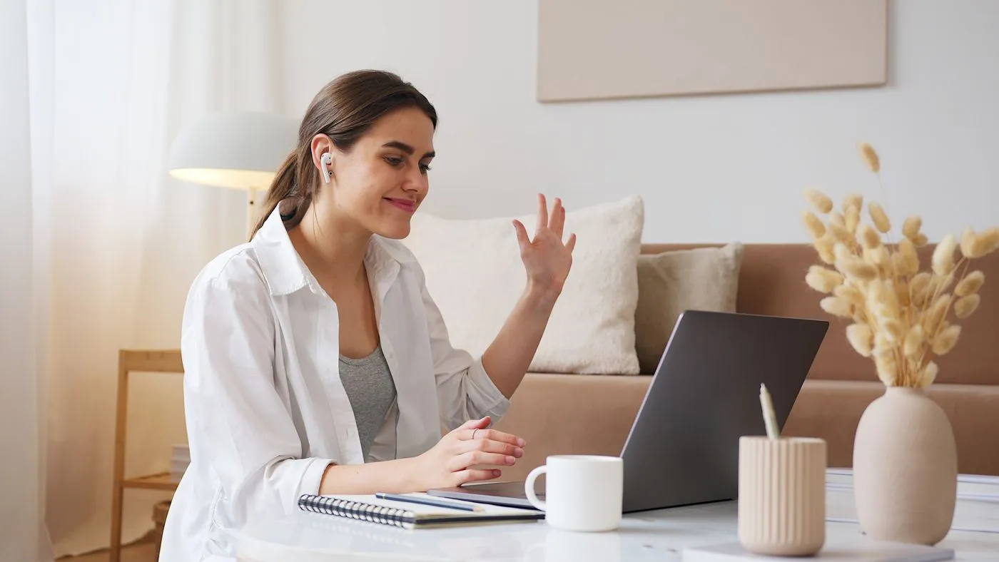 A woman waving hello on a video call